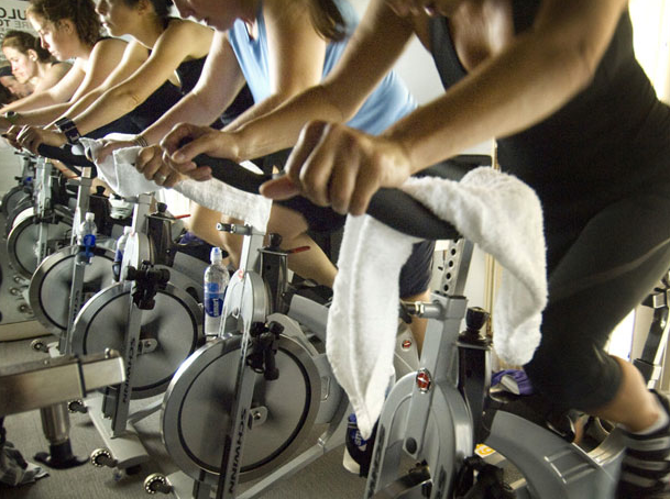 Spin Class with people riding stationary bikes exercising hard